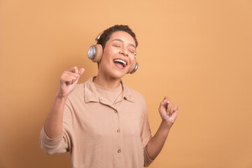 excited afro brazilian woman dancing to the music, care free in studio shot. leisure, fun, music, dance concept.