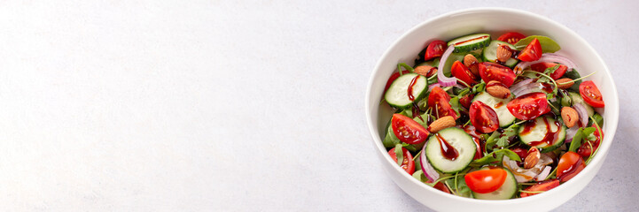 Healthy salad with tomato, cucumber, greens and nuts on light background, web banner