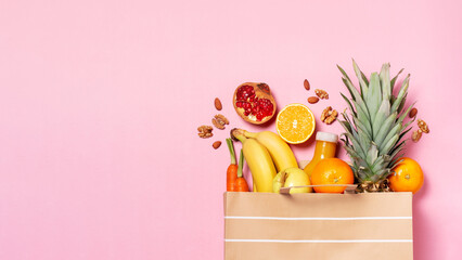 Fresh fruit and vegetables in paper bag on pastel pink background, top view, copy space