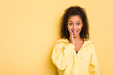 Young Brazilian curly hair cute woman isolated on yellow background shouts loud, keeps eyes opened...