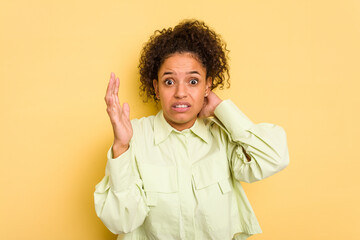 Young Brazilian curly hair cute woman isolated on yellow background screaming with rage.