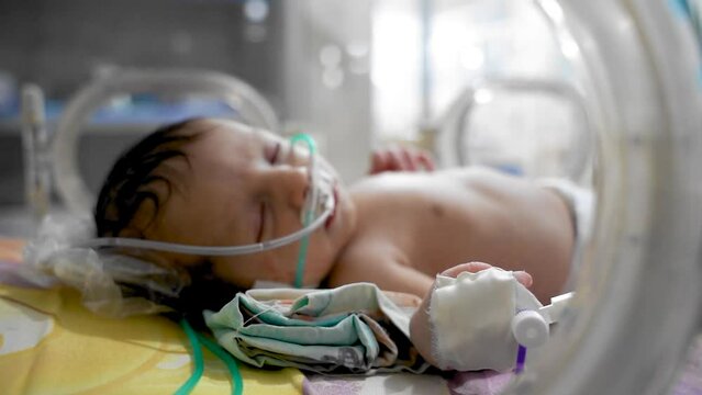 Closeup Lovely Little Newborn Baby Infant Lying In Incubators For Newborns, Newborn Baby Having The The Breathing Problem After Birth, Newborn In NICU, Neonatal Intensive Care Unit.