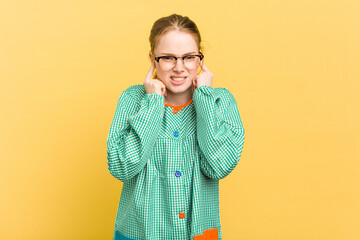Young caucasian child education teacher isolated on yellow background covering ears with hands.