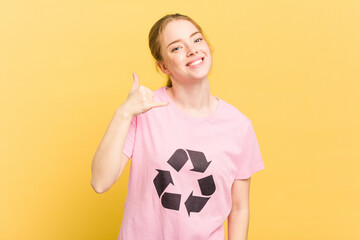 Young caucasian woman wearing a recycling t-shirt isolated on yellow background showing a mobile phone call gesture with fingers.