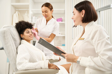 Fototapeta premium Two doctors consulting woman in beauty salon