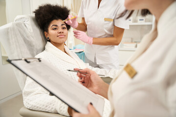 Obraz premium Two doctors consulting female in beauty salon