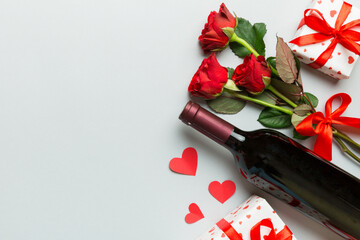 Fototapeta na wymiar Valentine's day composition with red wine, rose flower and gift box on table. Top view, flat lay. Holiday concept