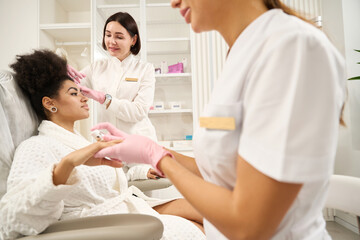 Cosmetologist consulting client during beauty injections in salon