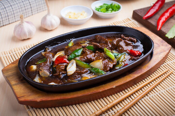 Photo of stir-fried beef with sauce on a hot plate, this dish is a typical Asian food