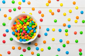Multicolored candies in a bowl on a colored background. birthday and holiday concept. Top view with copy space