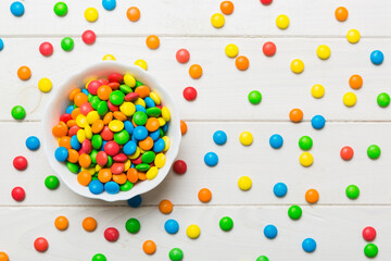 Multicolored candies in a bowl on a colored background. birthday and holiday concept. Top view with...