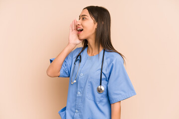 Young nurse colombian woman isolated shouting and holding palm near opened mouth.