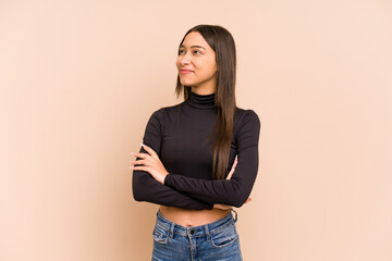 Young colombian woman isolated on beige background dreaming of achieving goals and purposes