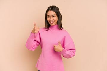 Young colombian woman isolated on beige background raising both thumbs up, smiling and confident.