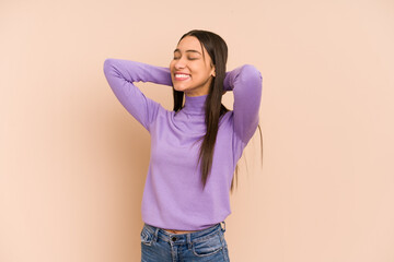 Young colombian woman isolated on beige background feeling confident, with hands behind the head.
