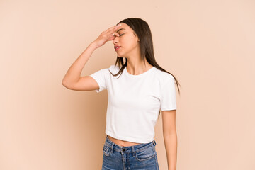 Young colombian woman isolated on beige background having a head ache, touching front of the face.