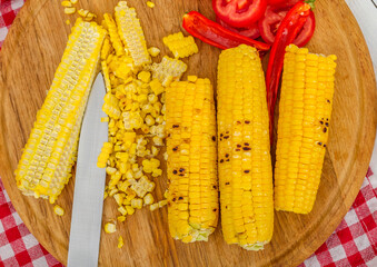 Top view of grilled corn with tomatoes on the cutting board