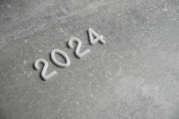 Year 2024 laid out in white numbers gray concrete background.