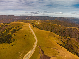 Mountain peaks covered with snow at the top and dry grass below and with clouds descending on the...
