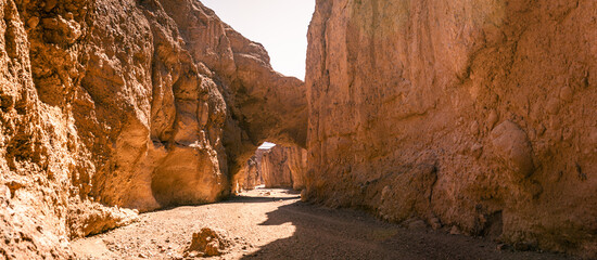 Orange, sandy, rock arch over path in Death Valley national park in america at sunny day