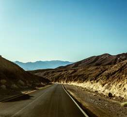Dark road with yellow line on side in middle desert in Death Valley in america
