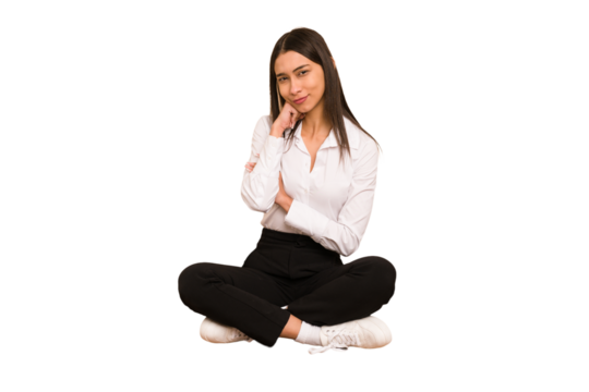 Young colombian woman sitting on the floor isolated looking sideways with doubtful and skeptical expression.