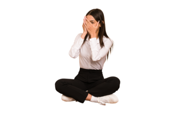 Young colombian woman sitting on the floor isolated blink through fingers frightened and nervous.