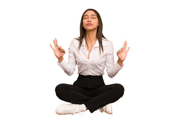 Young colombian woman sitting on the floor isolated relaxes after hard working day, she is...