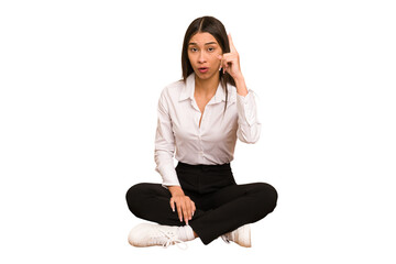 Young colombian woman sitting on the floor isolated having an idea, inspiration concept.