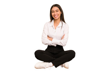 Young colombian woman sitting on the floor isolated who feels confident, crossing arms with...