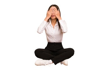 Young colombian woman sitting on the floor isolated afraid covering eyes with hands.