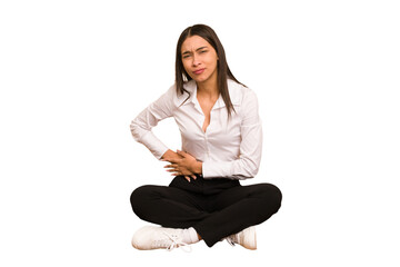 Young colombian woman sitting on the floor isolated having a liver pain, stomach ache.