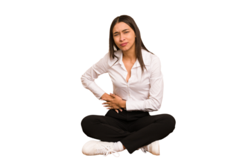 Young colombian woman sitting on the floor isolated having a liver pain, stomach ache.