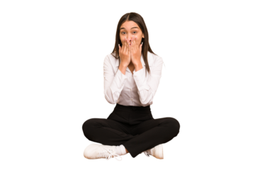Young colombian woman sitting on the floor isolated shocked, covering mouth with hands, anxious to discover something new.