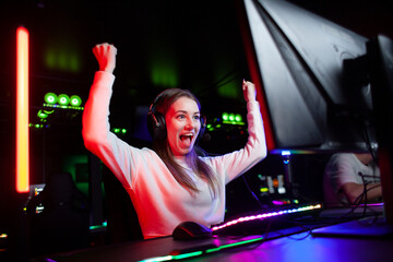 girl gamer in headphones sits at a computer and shouts at the monitor, crazy woman rejoices at victory