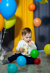 Fototapeta na wymiar Cute baby boy celebrating his First Birthday party. Baby boy playing with colorful balloons. The boy's birthday.