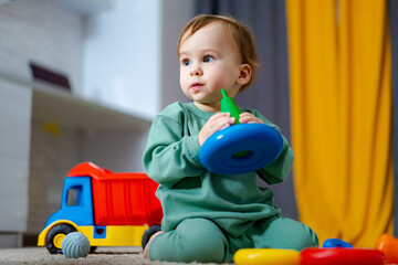 Baby boy playing with his colorful toys on floor at home. Child with educational toy. Early development.