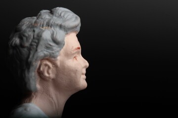 miniature figurine of an old woman on a black background: profile closeup 