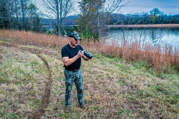 A photographer checking his camera at the lake on a wildlife photo shoot on Tims Ford.