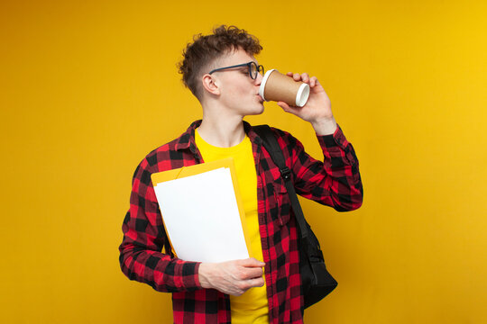guy student with a backpack and papers drinks coffee on a yellow background