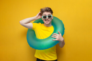 pensive guy on vacation with a swim ring scratching his head on a yellow background, the concept of...