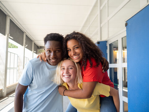 Three diverse student teenage friends having fun in high school
