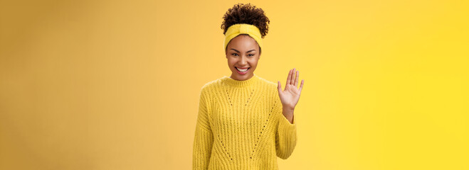 Cute timid friendly young girl wanna find new friends look pleasant smiling charmingly gladly waving hand hello hi gesture say welcome greeting heartwarming introduction herself, yellow background - obrazy, fototapety, plakaty