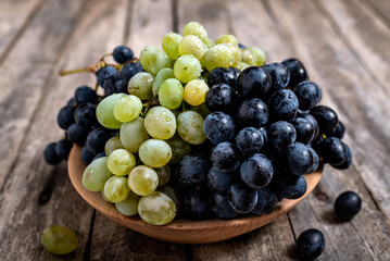 Bowl with grapes on wooden background