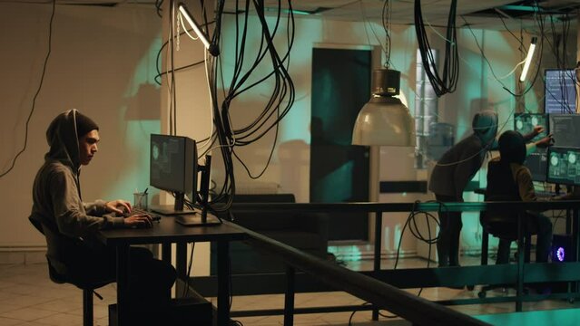 Spies using system vulnerability to exploit and break server, trying to hack computer at night. People working with multiple monitors to hack software, illegal hacktivism. Tripod shot.