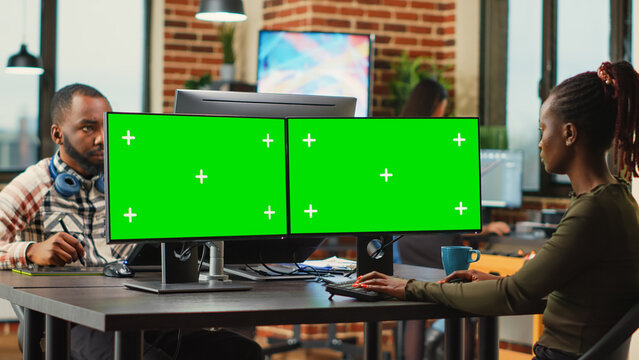 Creative agency employee using greenscreen display on computer, working with blank mockup template in office. Female worker looking at isolated copyspace and chroma key screen on pc.