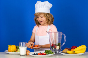 Portrait of chef child in cook hat hold carrot. Cooking at home, kid boy preparing food from vegetable and fruits. Healthy eating.