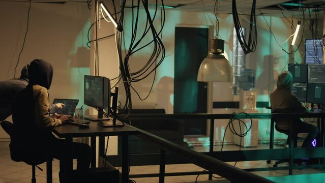 Hacking criminals using dark web to steal government data late at night, breaking firewall encryption. Hackers using trojan virus to create computer malware or security breach. Tripod shot.