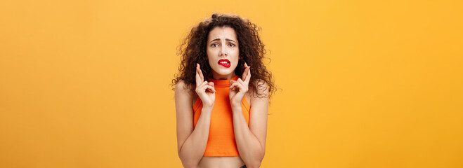 Worried and anxious silly caucasian female with curly hair in red lipstick and cropped top biting...
