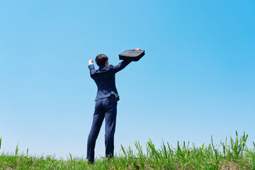 屋外でガッツポーズするビジネスマンの後ろ姿